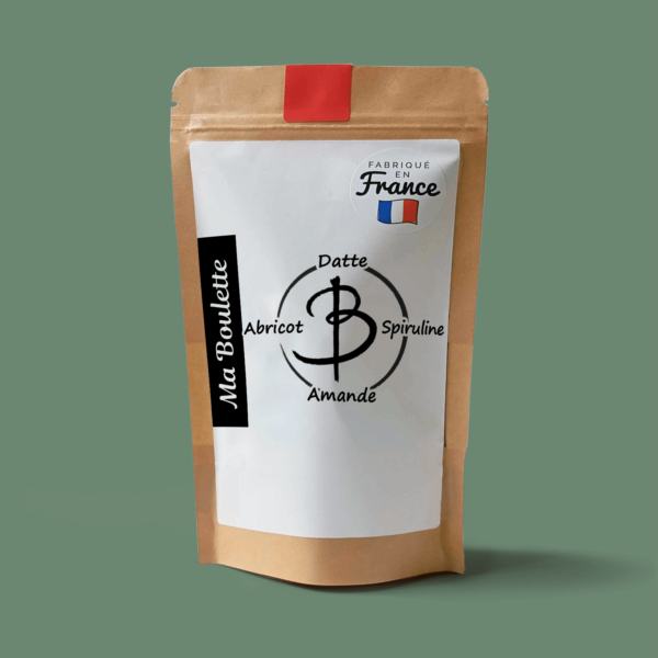Une photographie commerciale du produit energy balls Abricot-Amande-Spiruline sur un fond vert. Le produit est contenu dans un sachet craft avec une étiquette contenant l'inscription "Fabriqué en France"