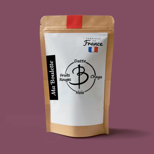 Une photographie commerciale du produit energy balls Fruits Rouges-Noix-Chaga sur un fond rose. Le produit est contenu dans un sachet craft avec une étiquette contenant l'inscription "Fabriqué en France"